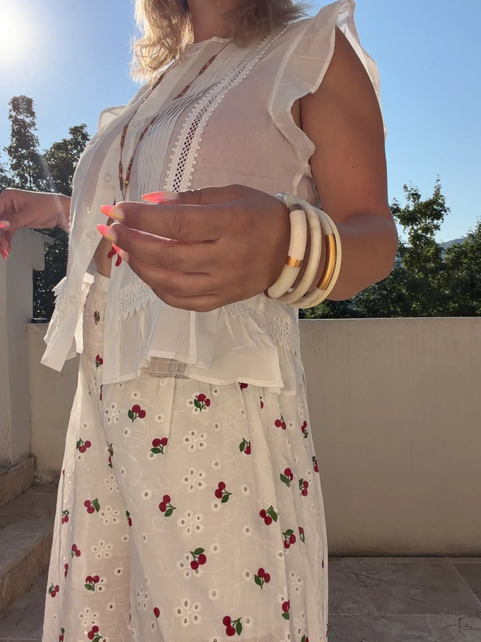 Blouse Paulette blanche portée avec pantalon cerise et bracelets
