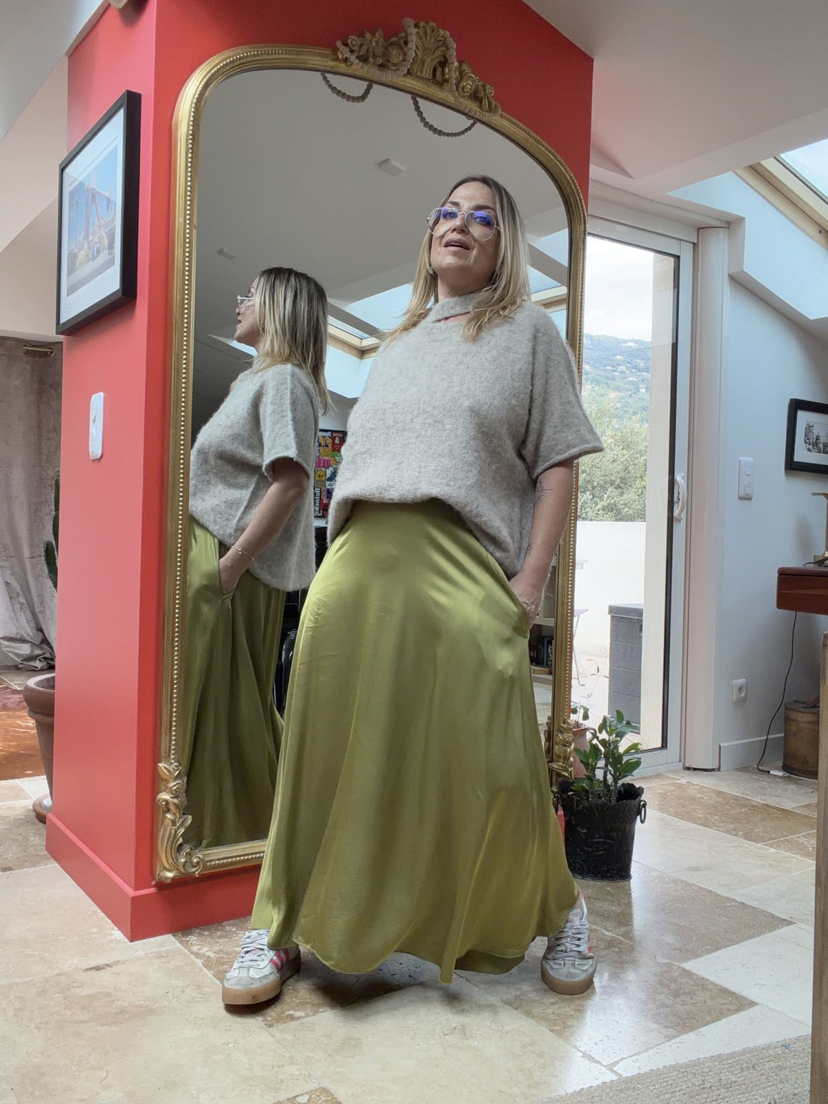 Pull asymétrique Émilie beige porté avec une jupe kaki, vue de profil